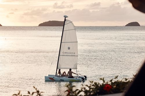 Two people sitting on a Hobie Wave catamaran on the water outside Kokomo Island Fiji.