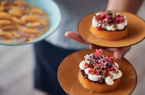 A waiter holding plates of dessert.