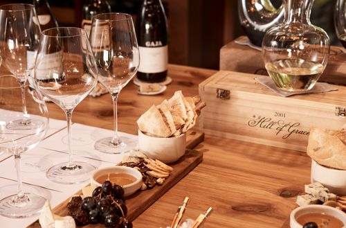 A private dining table within an intimate wine cellar with several large wine glasses set across the table.